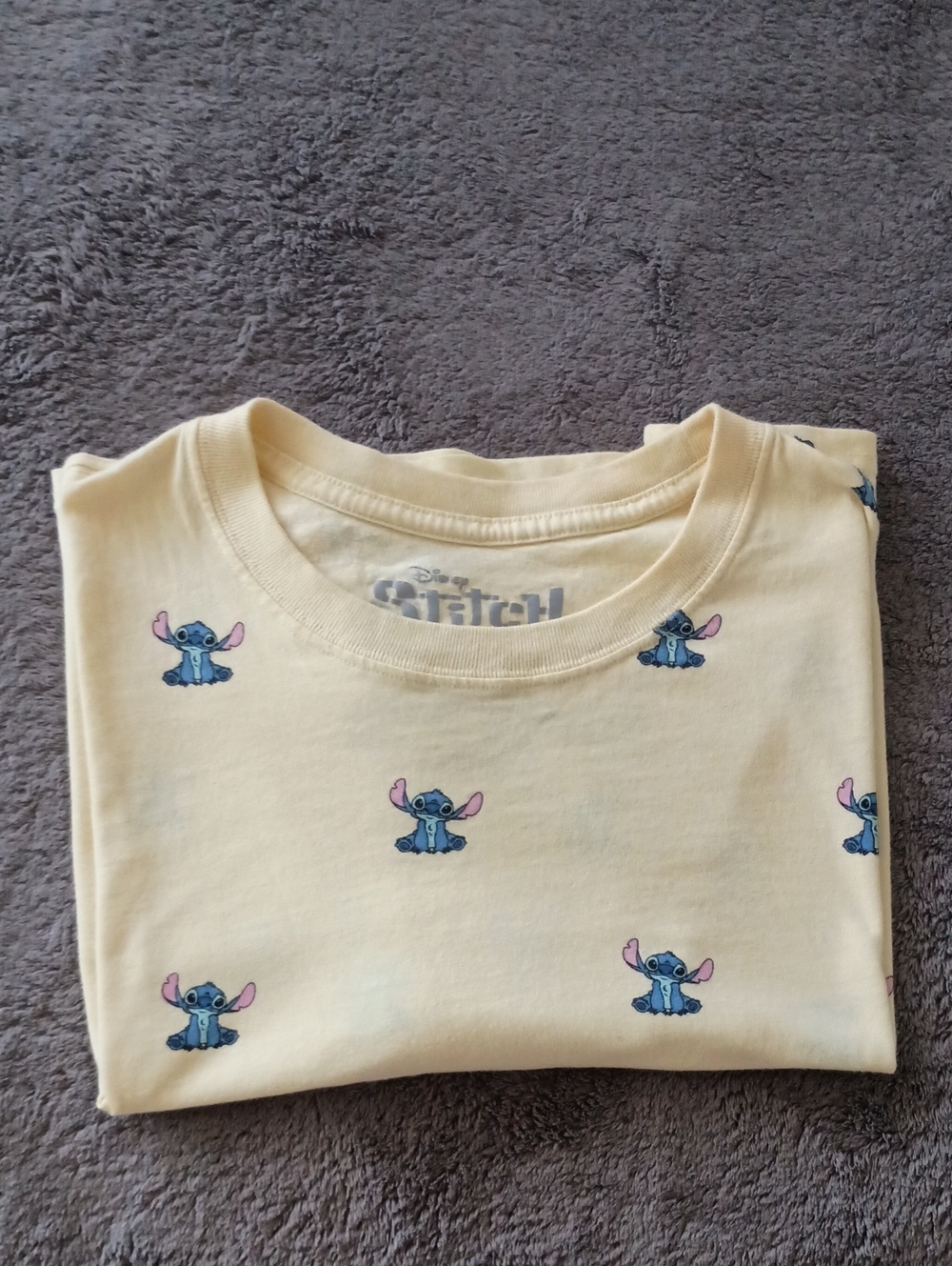 Disney Stitch t-shirt is a light yellow crew neck featuring a repeating all-over